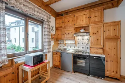 a kitchen with wooden cabinets and a stove and a window at Lovely 2 bedroom flat in Corso Italia with parking in Cortina dʼAmpezzo