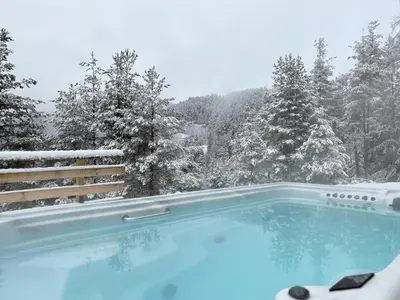 a hot tub with a view of a snow covered forest at Chalet Tschattlhof Dolomites in Ponte Nova