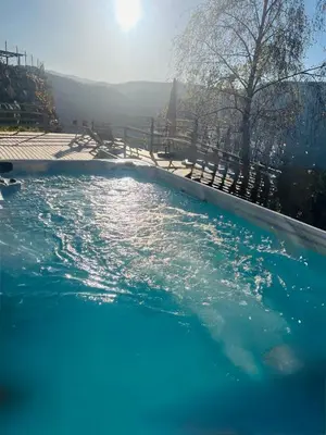 a swimming pool with blue water and a fence at Chalet Tschattlhof Dolomites in Ponte Nova