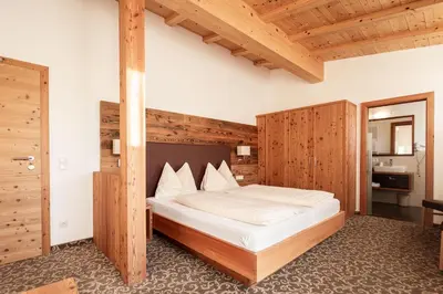 a bedroom with a large bed with a wooden wall at Garni Jasmin in Kastelruth