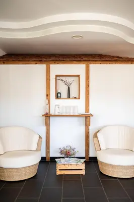 two white chairs in a room with a table at Garni Jasmin in Kastelruth