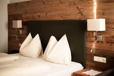 a bedroom with a bed with three pillows on it at Garni Jasmin in Kastelruth