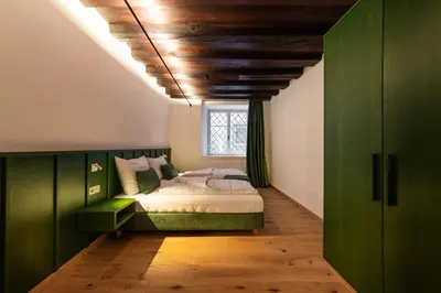 a bedroom with a green bed and a window at Casa Fellin Guesthouse in Vipiteno