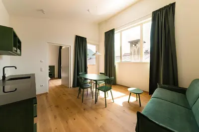 a living room with a green couch and a table at Casa Fellin Guesthouse in Vipiteno