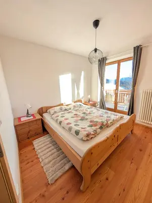 a bedroom with a large bed with a wooden floor at Appartamento LA REGINA un dolce rifugio tra api e natura in Tret
