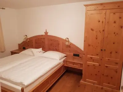 a bedroom with a large bed and a wooden cabinet at Neuhäusel-Hof Appartments in Avigna