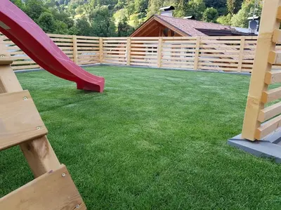 a playground with a slide and a wooden fence at Neuhäusel-Hof Appartments in Avigna