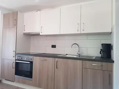 a kitchen with white cabinets and a sink at Neuhäusel-Hof Appartments in Avigna