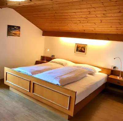 a large bed in a bedroom with a wooden ceiling at Appartement Primula - Haus Midi in Marlengo