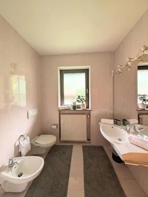 a bathroom with two sinks and a toilet and a window at Urlaub auf dem Bauernhof Schmidhof - große Terrasse, Pool und beste Lage in Caldaro