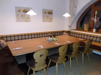 a large wooden table with chairs in a restaurant at Gasthof Alpenrose - Mühleben in Sarntal