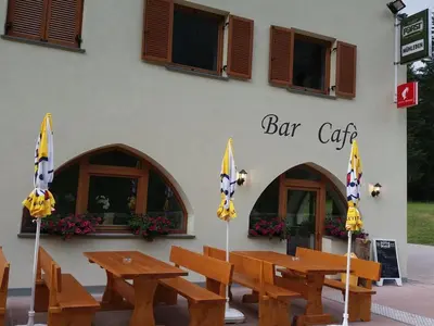 a restaurant with wooden tables and chairs in front of a building at Gasthof Alpenrose - Mühleben in Sarntal