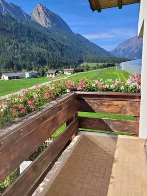 a wooden bench with flowers and mountains in the background at Ferienwohnung Pfitschtal in San Giacomo Val di Vizze