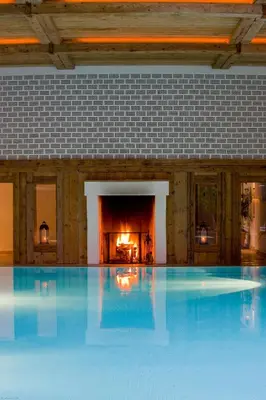 a large swimming pool in a building with a fireplace at Hotel Villa Irma in Merano