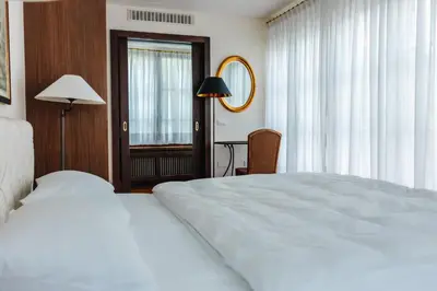 a bedroom with a large white bed and a desk at Hotel Villa Irma in Merano