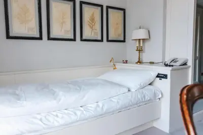 a white couch in a room with a lamp and pictures at Hotel Villa Irma in Merano