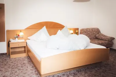 a bed with white pillows and a chair in a room at Prissianerhof in Tesimo