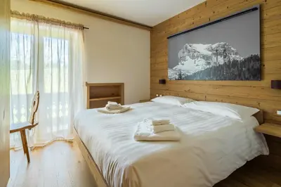 a bedroom with a large white bed with a television on the wall at Chalet Belvedere - Dolomiti Skyline in Cortina dʼAmpezzo