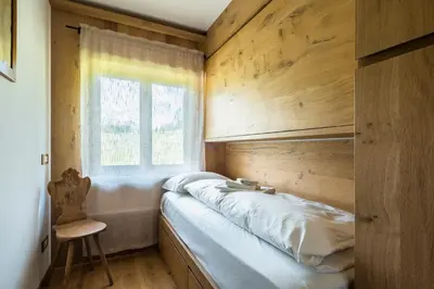 a bed in a room with a wooden wall at Chalet Belvedere - Dolomiti Skyline in Cortina dʼAmpezzo