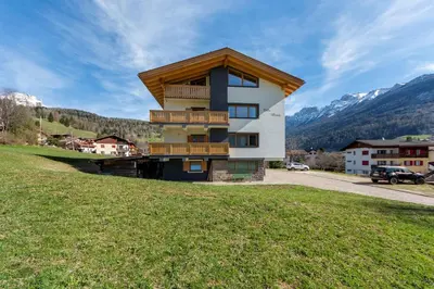 a house on a hill with mountains in the background at Villa Maria - Appartamento vista montagna in Moena