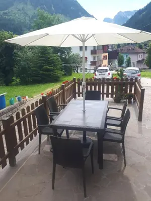 a table and chairs under an umbrella on a patio at Villa Maria - Appartamento vista montagna in Moena