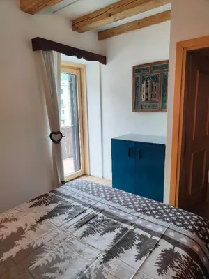 a bedroom with a bed with a blue cabinet and a window at So close to Sellaronda lifts! in Campitello di Fassa