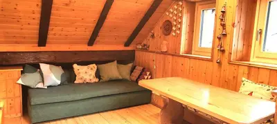 a room with a green couch in a wooden cabin at So close to Sellaronda lifts! in Campitello di Fassa