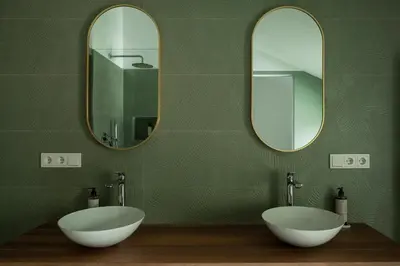 two sinks in a green bathroom with two mirrors at Hofgut Antlas in Collalbo