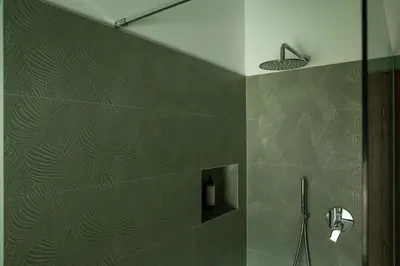 a bathroom with a shower with green tiled walls at Hofgut Antlas in Collalbo