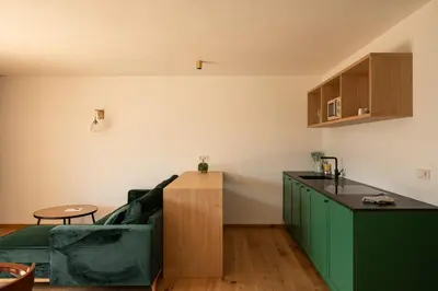 a living room with a green couch and a kitchen at Hofgut Antlas in Collalbo