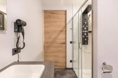 a bathroom with a tub and a phone next to a door at Villa Lara Zirbe in Castelrotto