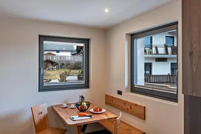 a dining room with a table and two windows at Villa Lara Zirbe in Castelrotto