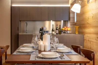 a wooden table with plates and wine glasses on it at Villa Speronella in San Martino di Castrozza