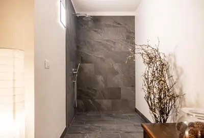 a bathroom with a shower with a stone wall at Villa Speronella in San Martino di Castrozza