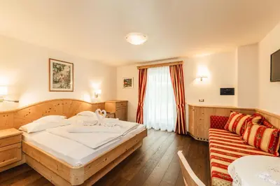 a table with a plate of breakfast food and a basket of bread at Hotel Daniel Apartments in Selva
