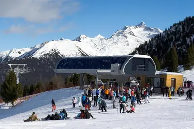 a group of people sitting in the snow near a ski lift at Residence Pfeifhofer in Campo Tures