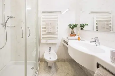 a white bathroom with a sink and a shower at Residence Pfeifhofer in Campo Tures