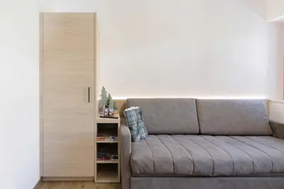 a living room with a couch and a book shelf at Appartamenti Terme Viola in Pozza di Fassa