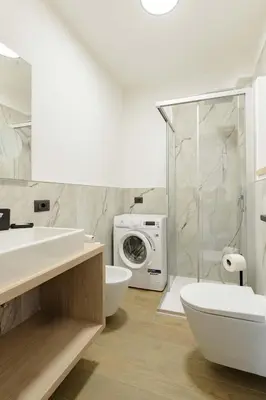 a bathroom with a washing machine next to a toilet at Appartamenti Terme Viola in Pozza di Fassa