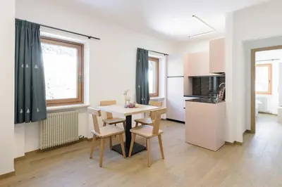 a kitchen and dining room with a table and chairs at Appartamenti Terme Viola in Pozza di Fassa