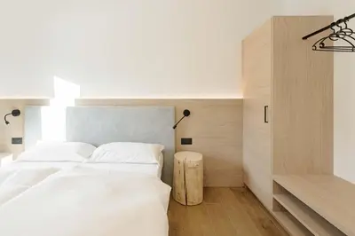 a bedroom with a large white bed and a table at Appartamenti Terme Viola in Pozza di Fassa