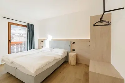a bedroom with a large bed and a window at Appartamenti Terme Viola in Pozza di Fassa