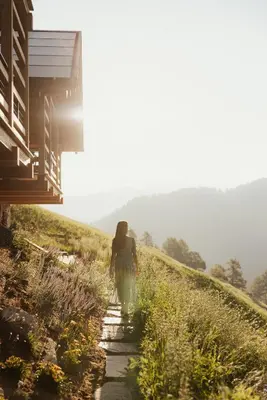 a woman walking down a path on a hill at Lominus Dolomites Luxury Chalet for 2 in San Martino in Badia