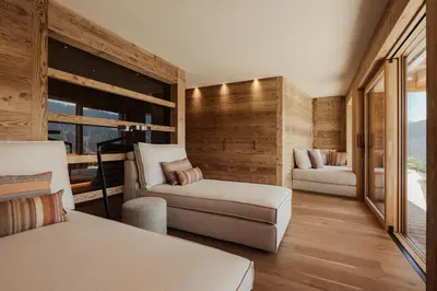 a bedroom with a couch and a chair and a window at Lominus Dolomites Luxury Chalet for 2 in San Martino in Badia