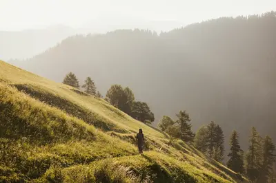 a man standing on top of a grassy hill at Lominus Dolomites Luxury Chalet for 2 in San Martino in Badia