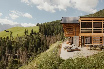 a house on the side of a hill with chairs at Lominus Dolomites Luxury Chalet for 2 in San Martino in Badia