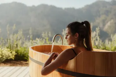 a woman is sitting in a wooden bath tub at Lominus Dolomites Luxury Chalet for 2 in San Martino in Badia