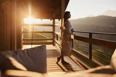 a woman standing on the balcony of a house at Lominus Dolomites Luxury Chalet for 2 in San Martino in Badia