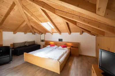 a bedroom with a large bed and a tv at Göllerhof in Caldaro