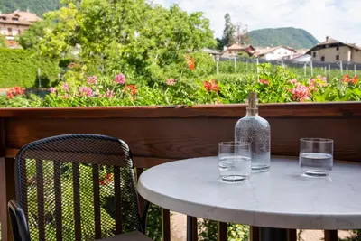 a table with a bottle and two glasses on a balcony at Göllerhof in Caldaro